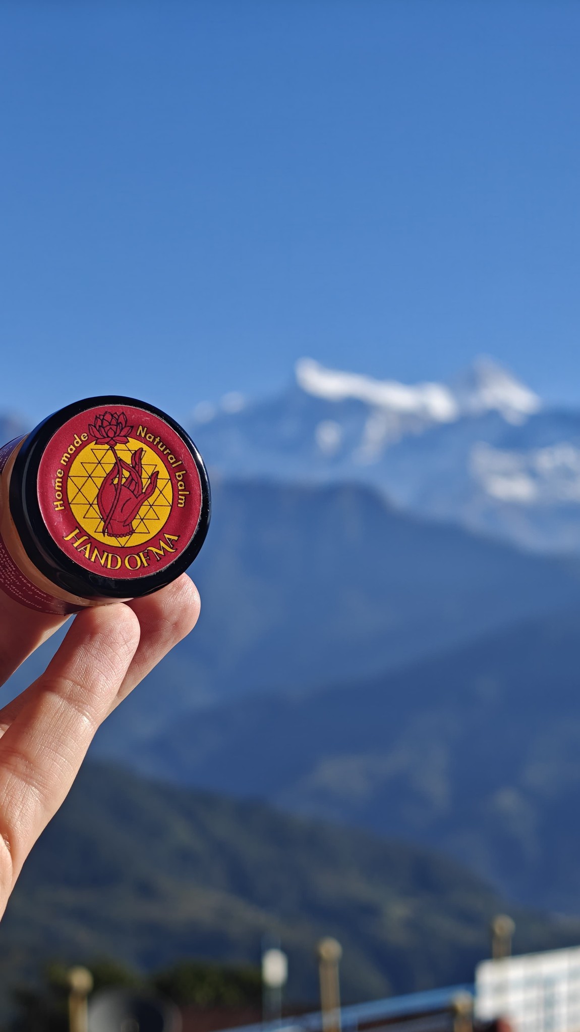The Hand of Ma balm held against the Himalaya